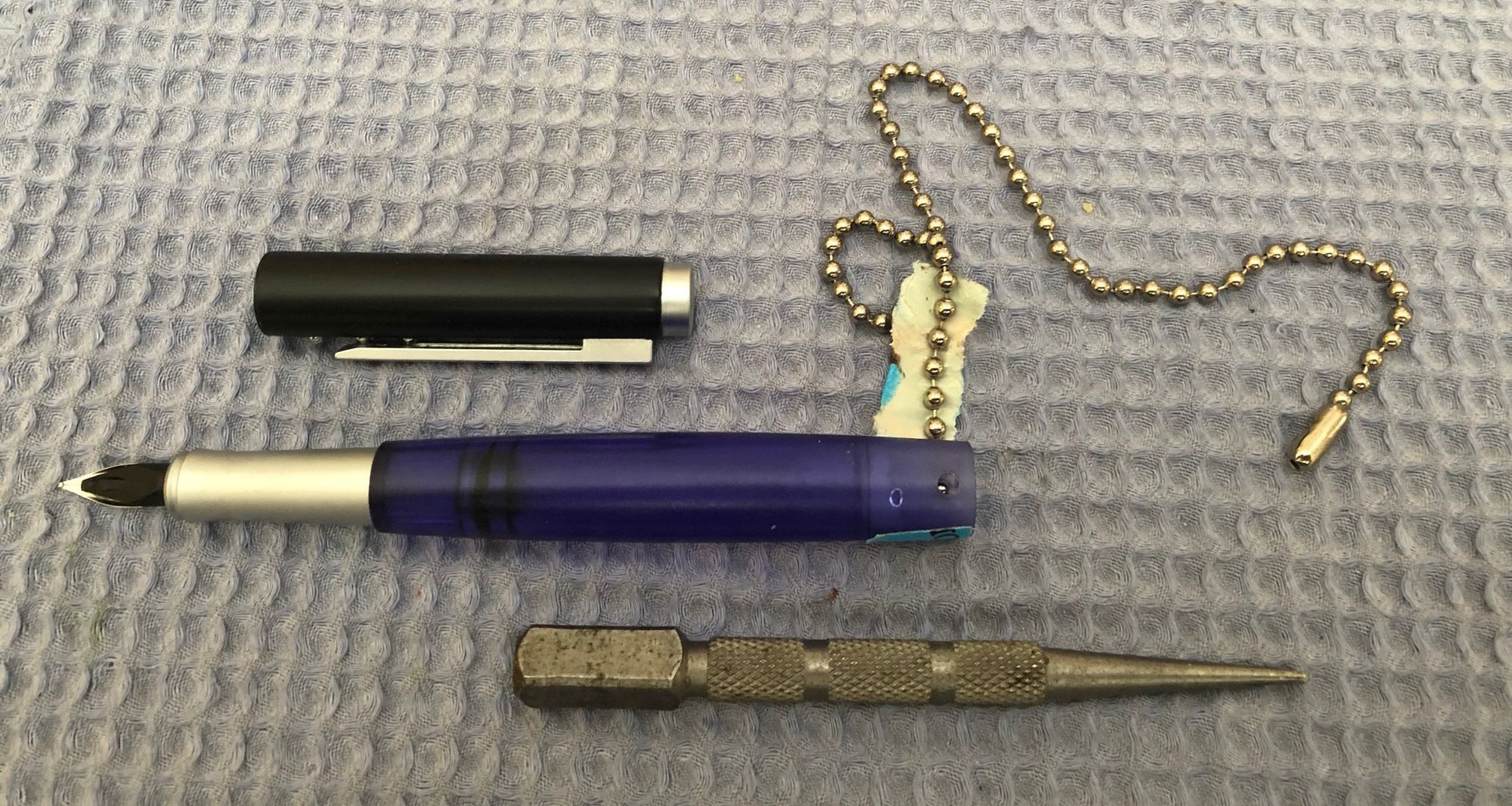 Disassembled pen with a nail set and pull chain.