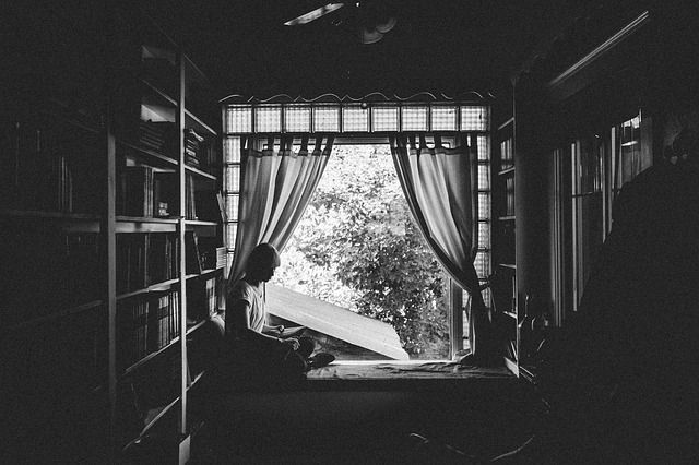 A person reading in a shady room