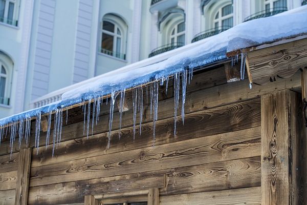 A picture showing an ice dam and icicles on an older wooden building.